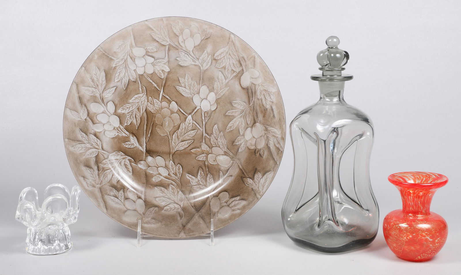 (4) Pcs Glassware: (4) Pcs glassware, c/o embossed amethyst plate (11-1/4" dia), Holmegaard pinch bottle (10-1/2" h), Mdina Glass Malta orange swirl vase (3-7/8" h), Kosta Boda candle holder (3" h), chip to back of plat