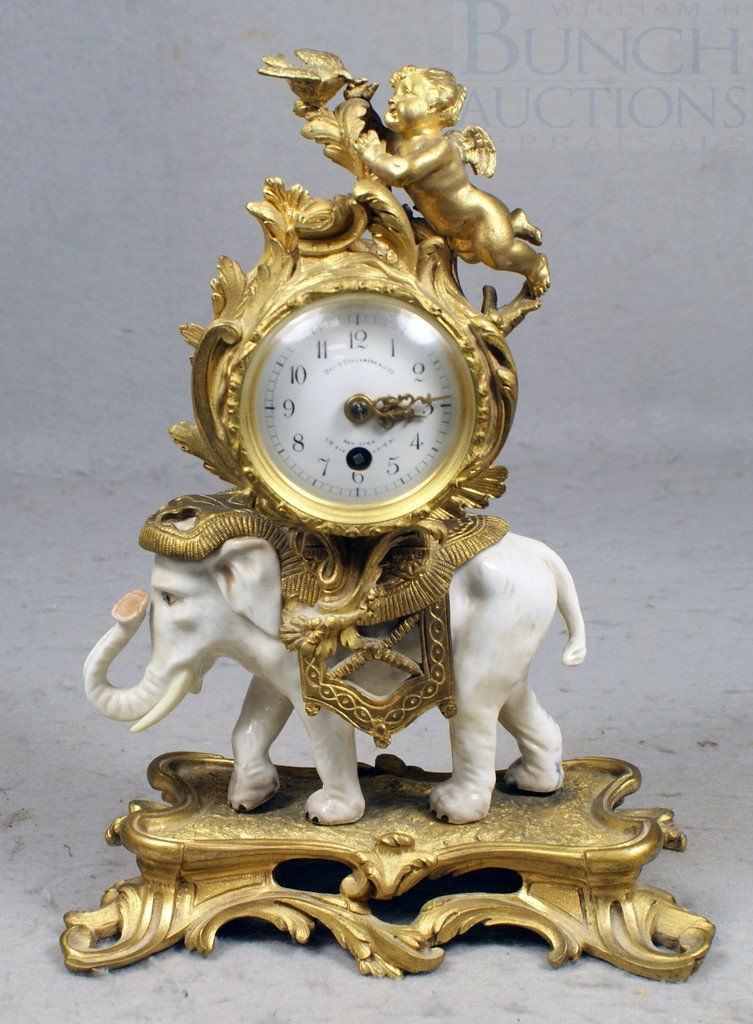 E Courtin French gilt bronze and porcelain elepha: E Courtin French gilt bronze and porcelain elephant mantle clock, the gilt bronze case crested by a winged putti holding a bird, resting on a howdah seat on a white porcelain elephant, one back leg wi