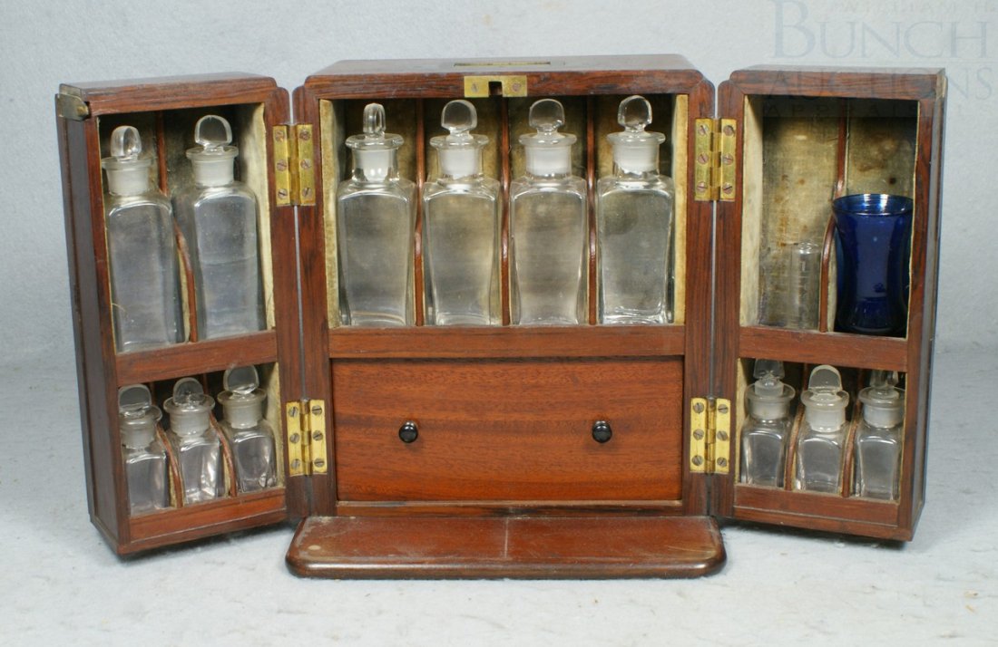 Mahogany apothecary cabinet, fitted interior with: Mahogany apothecary cabinet, fitted interior with 12 bottles, 2 likely missing, deep storage drawer with tray, containing a gold balance scale with 3 weights, 9" h, 7 3/4" w, 6" d, missing 1 escutcheo