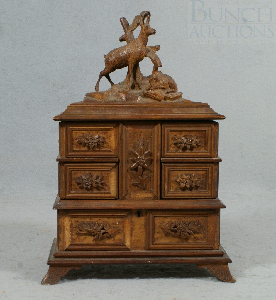 Carved Black Forest jewelry box, lift lid with de: Carved Black Forest jewelry box, lift lid with deer carved crest, 4 swing open compartments, concealing a storage area in base, on carved feet, 9" w, 12 1/2" h, 2 small pcs trim missing, small chip at