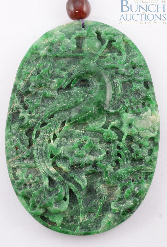 Oval Chinese carved serpentine stone medallion, : Oval Chinese carved serpentine stone medallion, dragon and phoenix bird design on opposite sides, 4" x 2 3/4", on a cord with amber bead