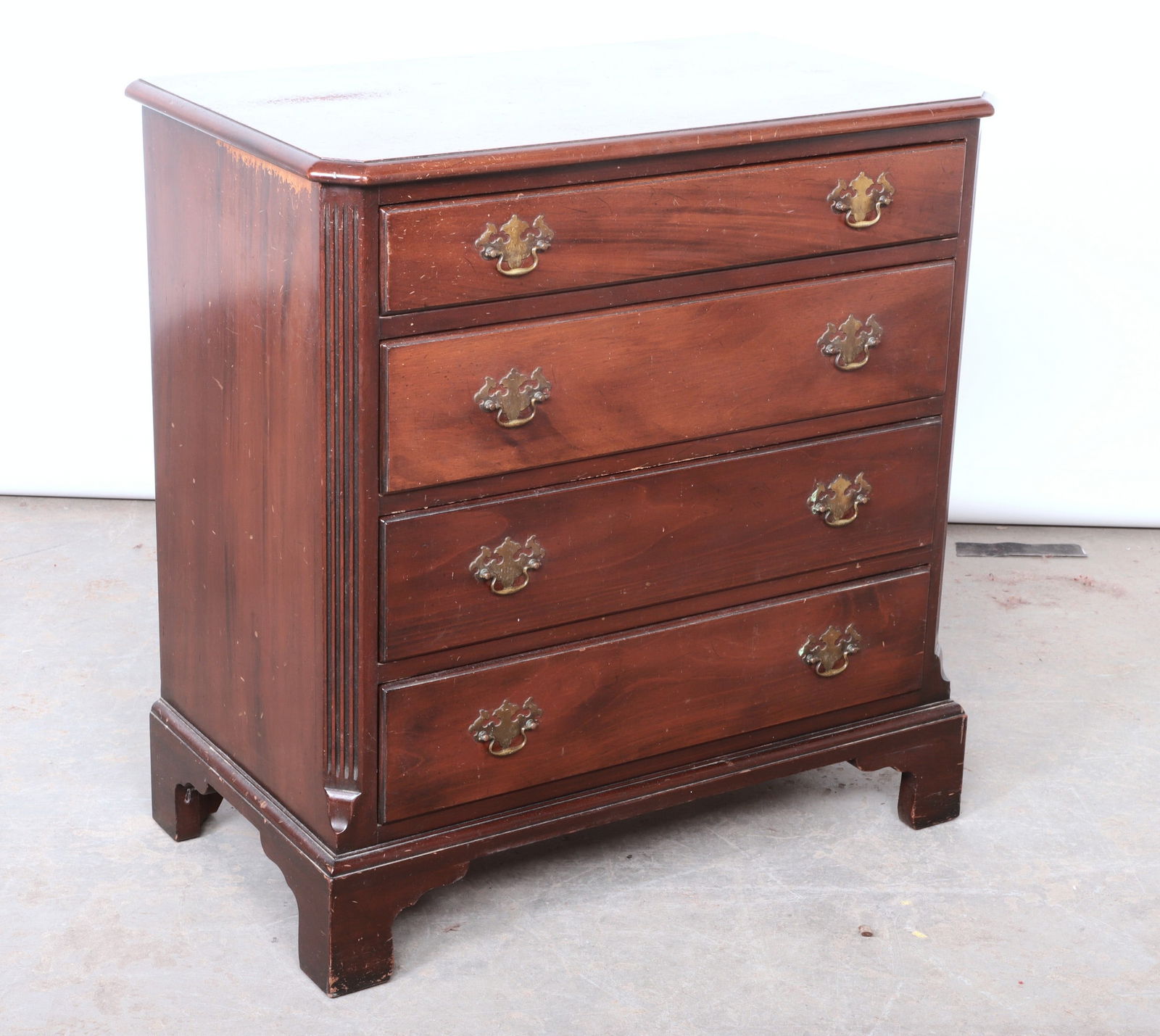 Kittinger Mahogany Finished Chairside Chest: Kittinger Buffalo mahogany finished chairside chest, clipped corner top, over 4 drawers, with batwing brass pulls, over bracket feet. 31"H x 29 1/2"W x 17"D. worn and scratched top.