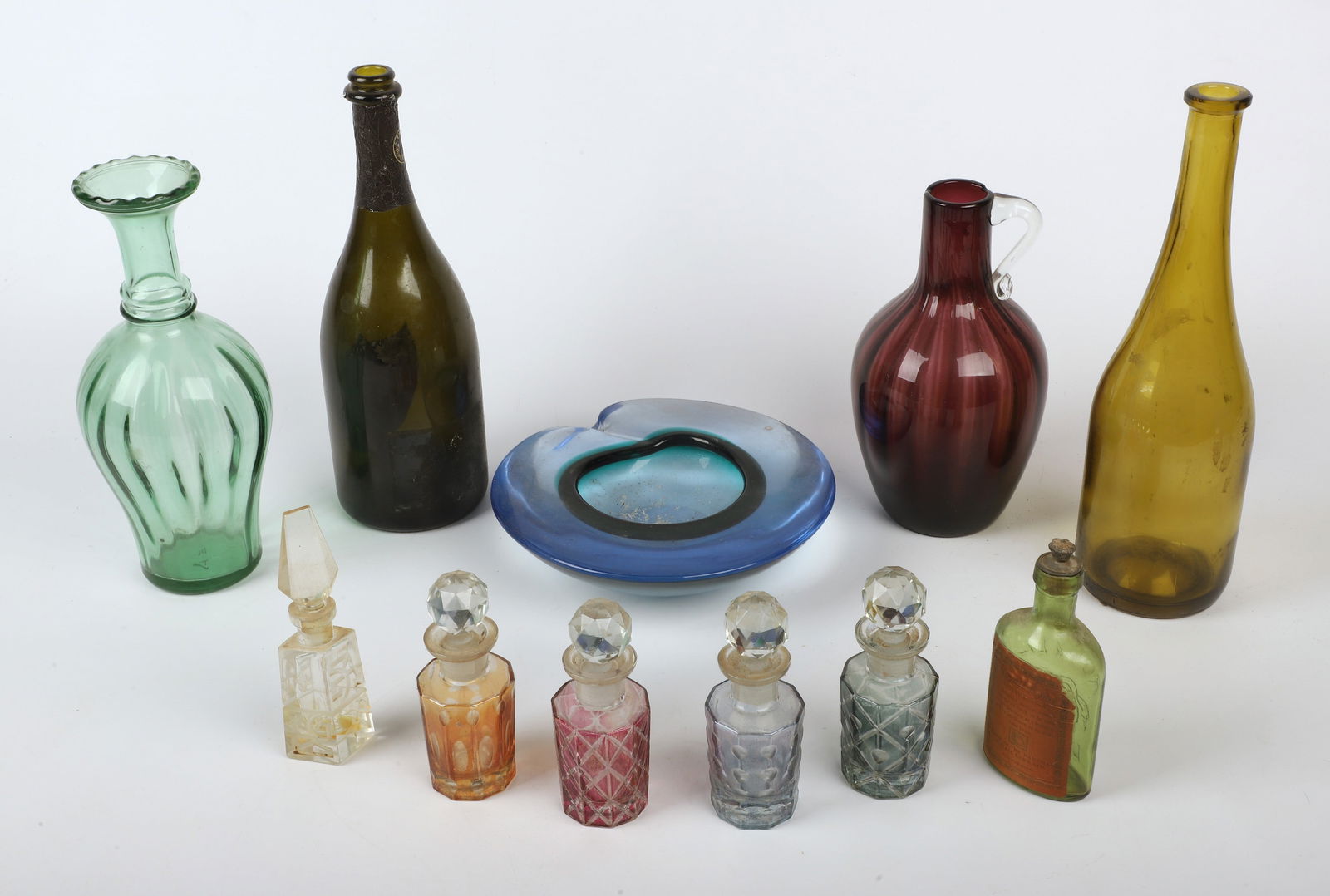 (11) Pieces of glassware: (11) Pieces of glassware, including unsigned art glass ashtray (8-1/8" x 7-7/8"), (4) flash glass scent bottles (5" h), cut glass perfume bottle (5-3/4" h), Cuvee Dom Perignon 1992 bottle, Royal Lyme