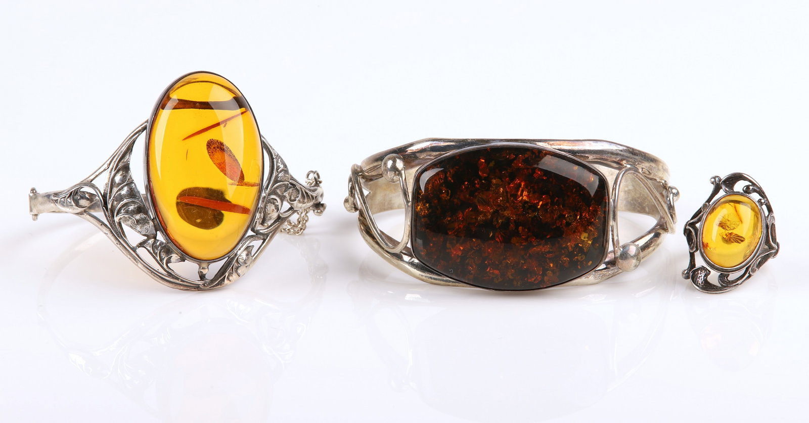 (3) Sterling and amber cuff bracelets and ring: (3) Sterling and amber cuff bracelets and ring to include a UTC stamped Nouveau style scroll pierced amber cabochon centered ring, sz 7, a similarly designed hinged Nouveau style scroll pierced amber