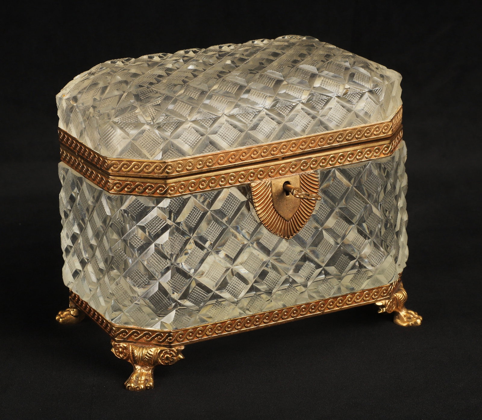 Gilt bronze mounted cut glass casket: Gilt bronze mounted cut glass casket, raised on paw foot, in diamond and texture decoration, chamfered corners, with key, 6 1/2"L x 4" D x 5 1/2"H, remnant glue at interior, not related to any damage.