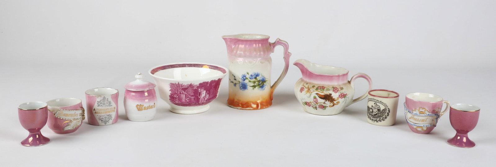 (10) Pieces pink lustre porcelain: (10) Pieces of pink lustre porcelain, including "The Mother's Grave" mourning bowl (6-1/4" dia x 3-1/4" h), "A Presentation from Aberystwyth" mug, Mottahedeh Historic Charleston Reproductions "A Prese