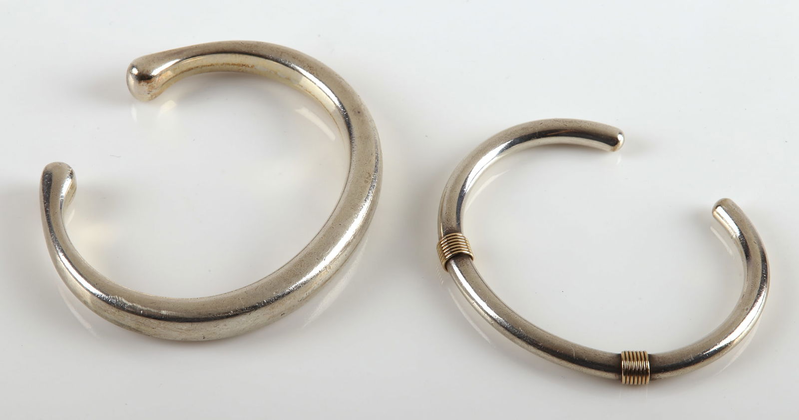 (2) Georg Jensen Sterling Cuff Bracelets: (2) Georg Jensen sterling cuff bracelets to include No.215, design by Flemming Eskildsen along with a Georg Jensen sterling cuff bracelet with 18K yellow gold wrapped highlight,No. A 60 A , 75.1 DWT