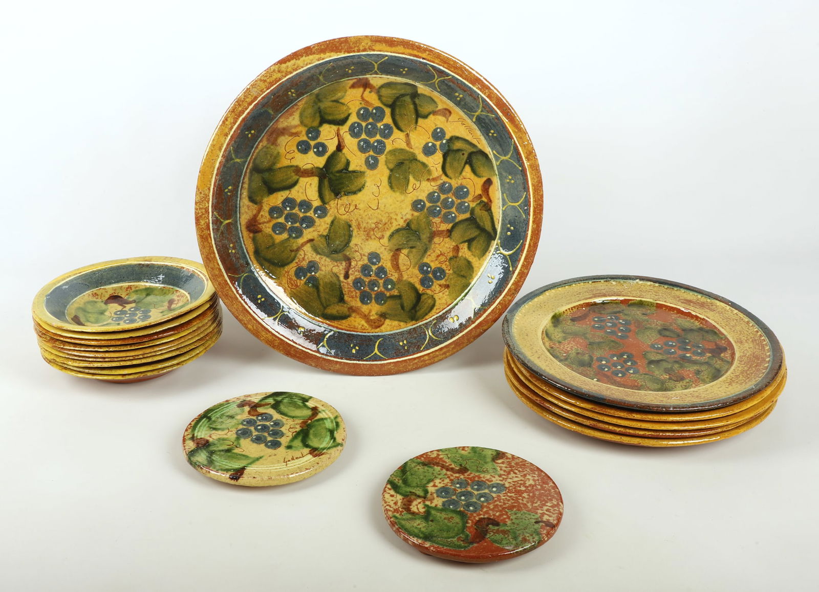 (17) Pieces Redware Artist Made Pottery: (17) Pieces Redware Artist Made Pottery to include (9) bowls, 9" dia, (5) plates, (1) of which with inverse decorated trim, 12 3/4" dia, a serving platter, 16 3/4" dia along with (2) trivets, each sig