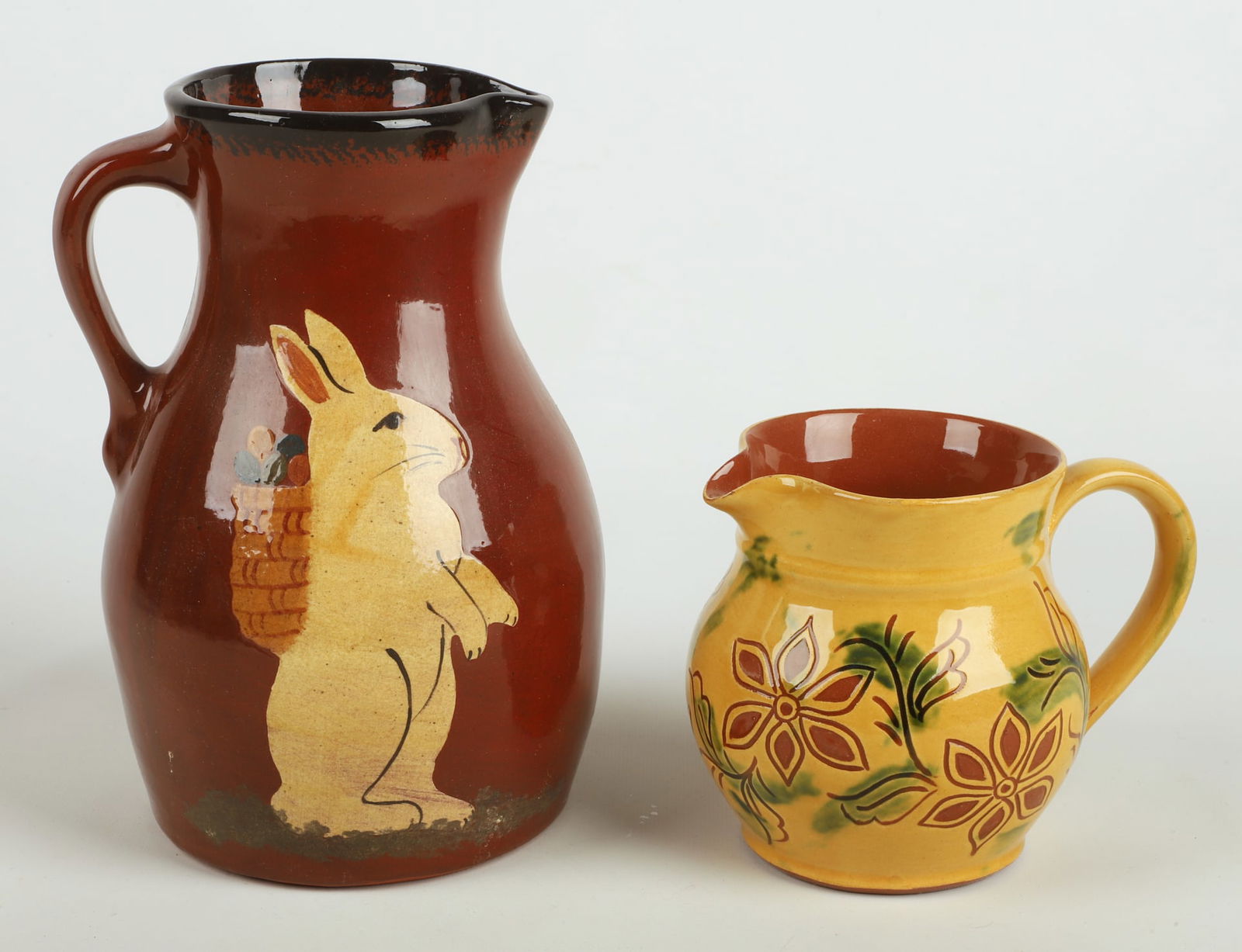 (2) Redware pottery pitchers: (2) Redware pottery pitchers, including Ned Foltz 2000 with slip decorated Easter bunny (9-1/2" h), Breininger 2001 with sgraffito floral decoration (5-1/4" h)