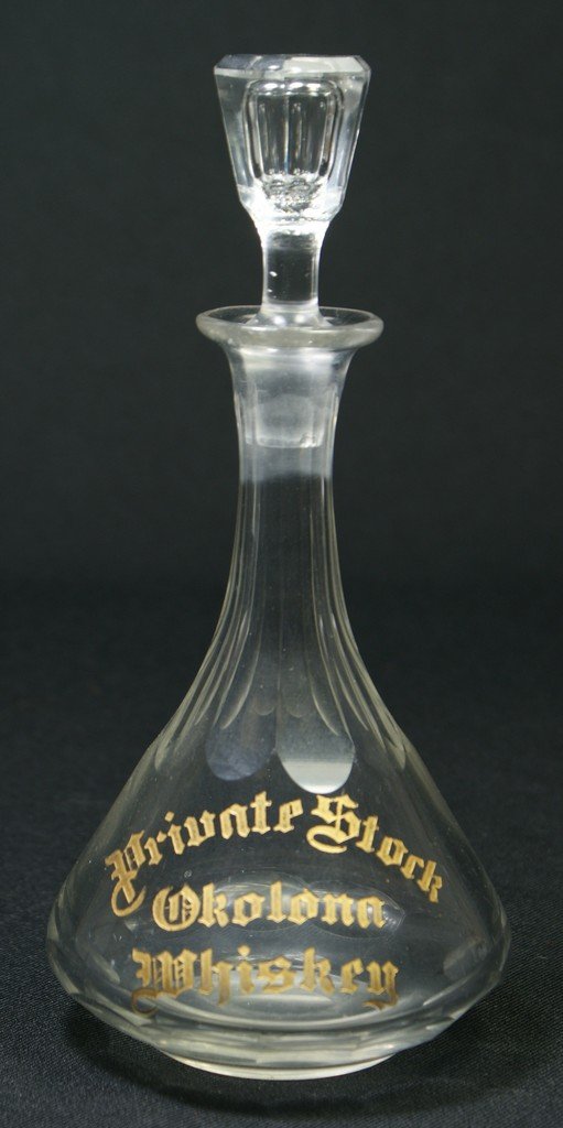 Clear glass back bar bottle with etched and gilt: Clear glass back bar bottle with etched and gilt decoration, PRIVATE STOCK OKALONA WHISKEY, 8 1/2", stopper with chip at bottom