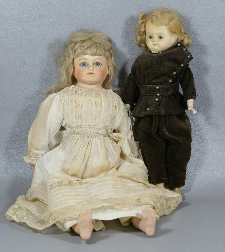 2 Wax over papier mache shoulder dolls, the larger is a: 2 Wax over papier mache shoulder dolls, the larger is a heavier compo with fixed blue glass eyes wearing original clothes and mohair wig, cloth body and compo lower limbs, smaller 1860s era boy with b