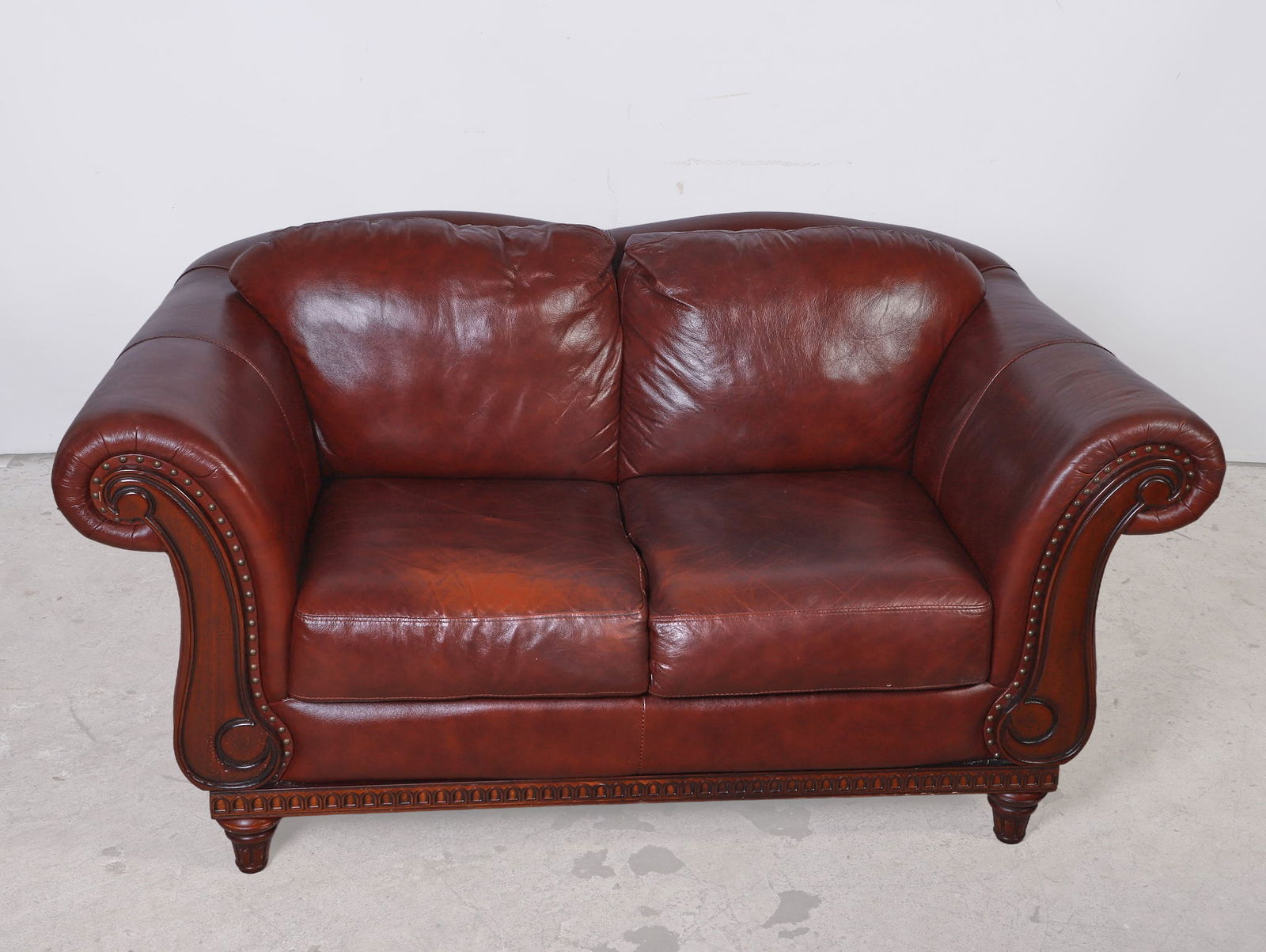 Contemporary Leather Love Seat: Contemporary leather love seat, tobacco/burgundy leather, scrolled arms, stylized turned and fluted bun feet, 36"H x 68"W x 37"D
