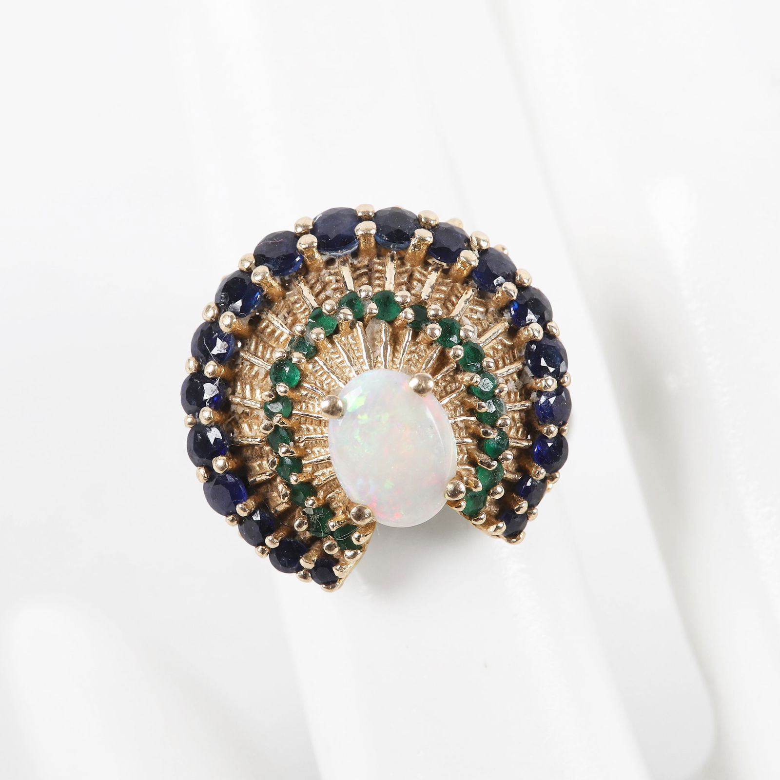 14K Yellow Gold Multi-Stone Cocktail Ring: 14K Yellow Gold Multi-Stone Cocktail Ring, a braided textured fan form cocktail ring with (19) graduated round cut sapphires, 1.2mm through 2.8 mm, .78 CTTW, (19) 1 mm emeralds and an 8mm x 6 mm centr