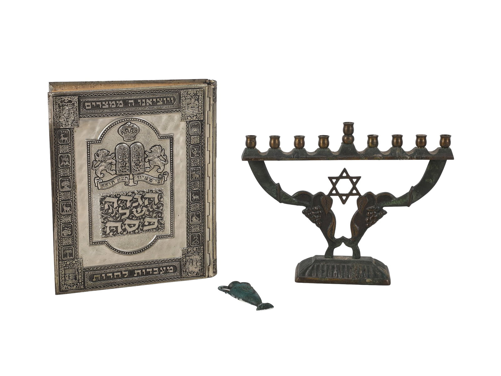 (3) Judacia Lot: (3) Judacia Lot (3) Judacia lot to include a Haggadah in silver binding, a 9 1/4"W x 7"H brass Israeli made menorah, and a 3" urn form mezuzah