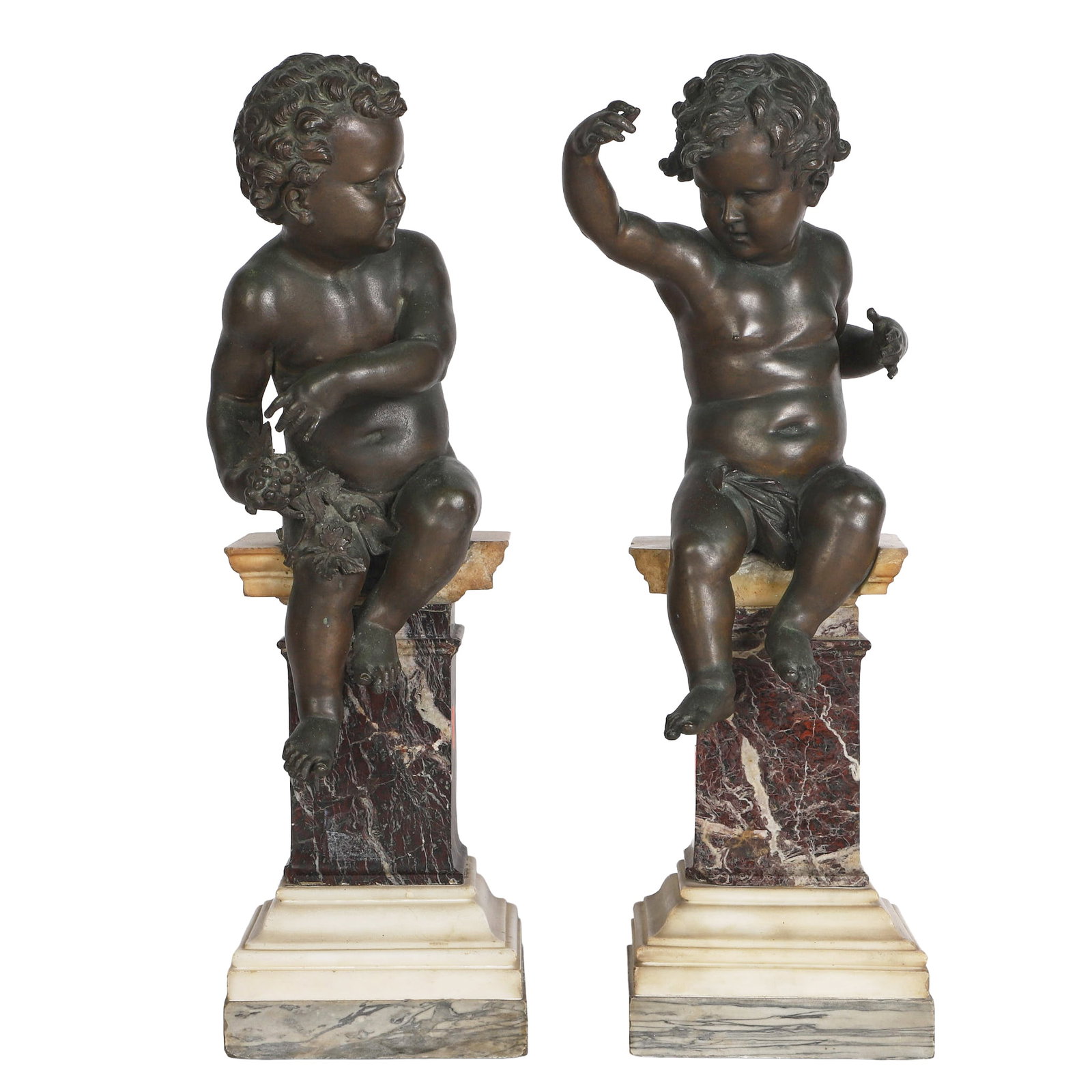 Italian Bronze Putti on Marble: Gorgeous duo of Italian putti figures in bronze perched atop marble pedestal bases, one with grapes and the other with arms raised. Chipped corners noted on both pedestals, with the arms raised