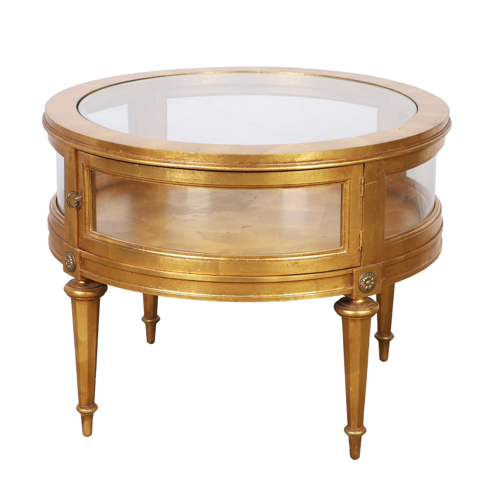 Louis XVI Style Giltwood & Glass Vitrine Table: Louis XVI style giltwood vitrine display table with circular glass inset top, curved glass panels with hinged door, raises on tapered legs and accented with carved rosettes, 23"h x 28" w