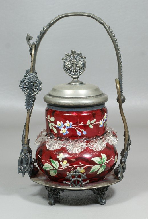 Enameled cranberry glass pickle castor with clear: Enameled cranberry glass pickle castor with clear ruffled apron, a Meriden Co silverplated base, lid and tongs, 9-1/2" high