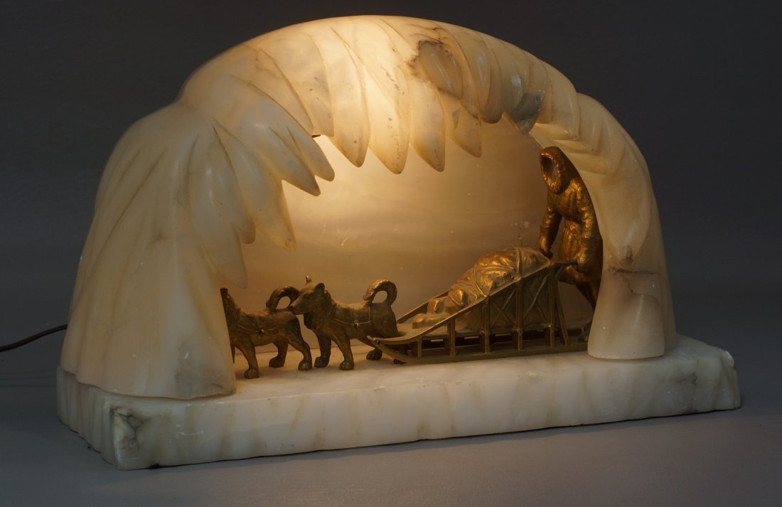 Carved Alabaster Ice Cave and Gilt Metal Dogsled Lamp,: Carved Alabaster Ice Cave and Gilt Metal Dogsled Lamp, the cave is lose from base, figure's face missing, 9" h, 15" w, 5" d