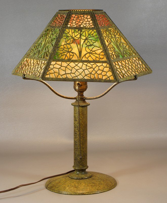 Bronze patinated Bradley and Hubbard art deco table: Bronze patinated Bradley and Hubbard art deco table lamp, filigree overlay hexagonal shade on green, caramel, and purple slag glass, 13 1/4" d, signed and numbered 4425 on base, 19 1/4" high overall