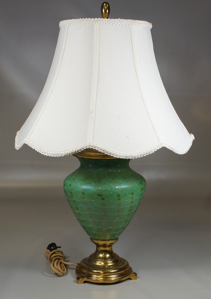 Green art glass lamp, white drapery with silver/blue: Green art glass lamp, white drapery with silver/blue spotting, interior light gold/green in color, unsigned, glass body 8" tall, lamp 24" overall