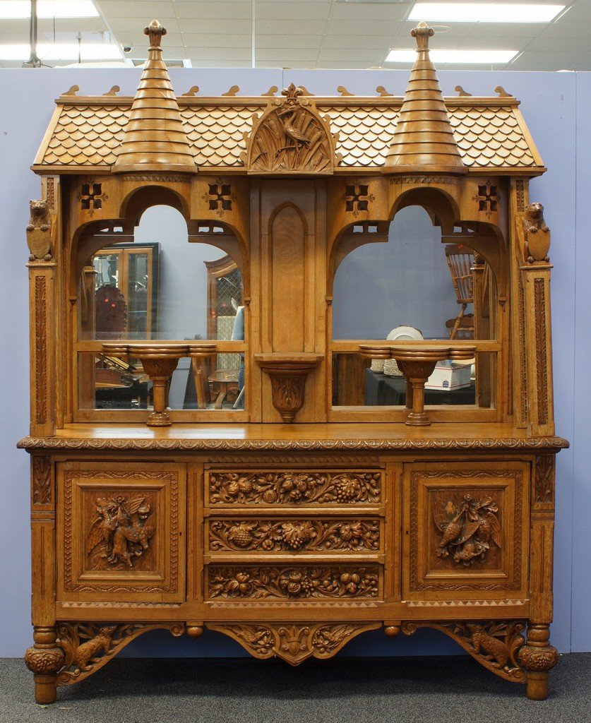 Castle themed carved oak sideboard, hooded top with: Castle themed carved oak sideboard, hooded top with shingled roof and twin towers flanking a shore bird carved panel, base with hanging game and carved fruit motif, 79" w, 98" tall, 27" d, German, 19t