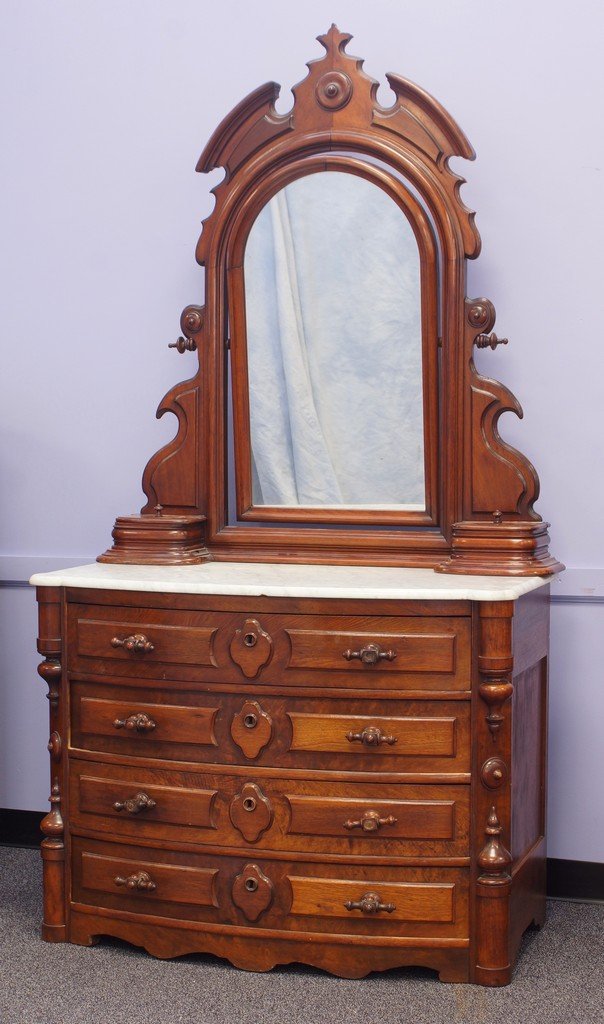 Carved walnut Victorian marble top bureau with four: Carved walnut Victorian marble top bureau with four drawers in base, unusual turned t-shaped handles, top with enclosed swinging mirror with gloves boxes, 43" wide, 86" high