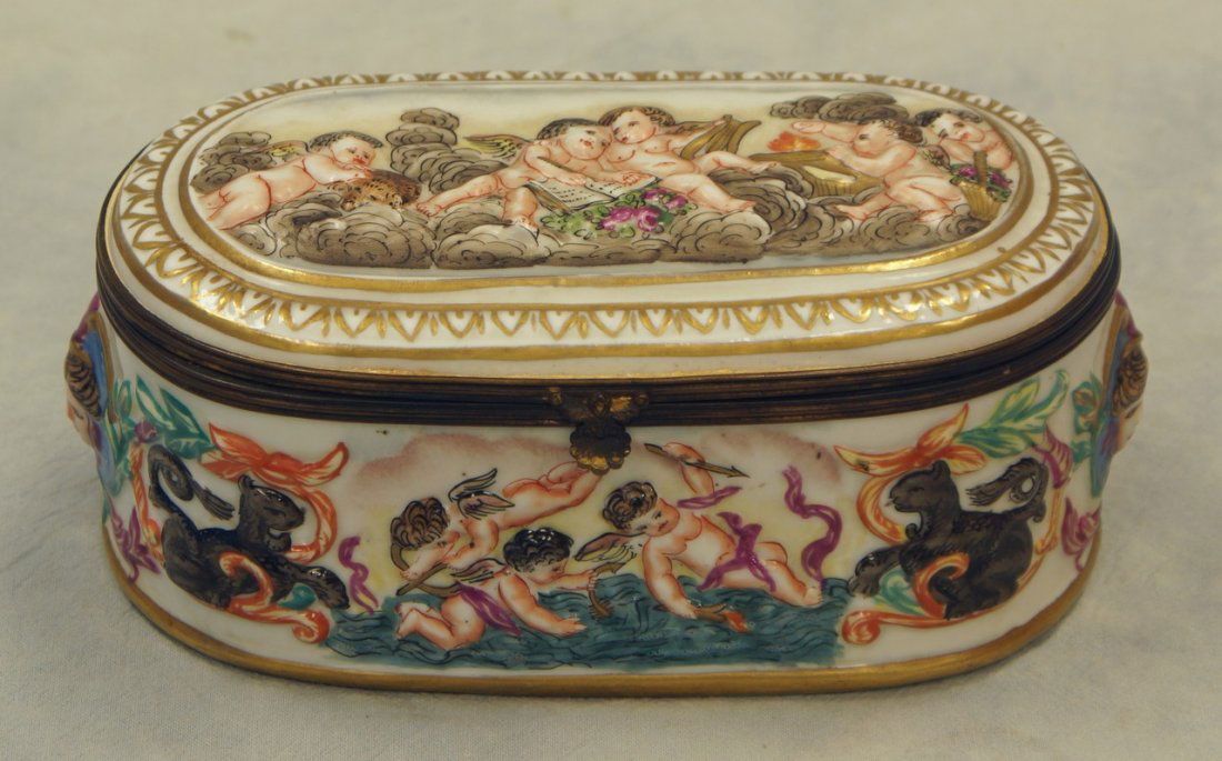Oval Capodimonte lift lid dresser box decorated with: Oval Capodimonte lift lid dresser box decorated with putti in landscape scenes height: 3 in. Length: 6 1/2 in.
