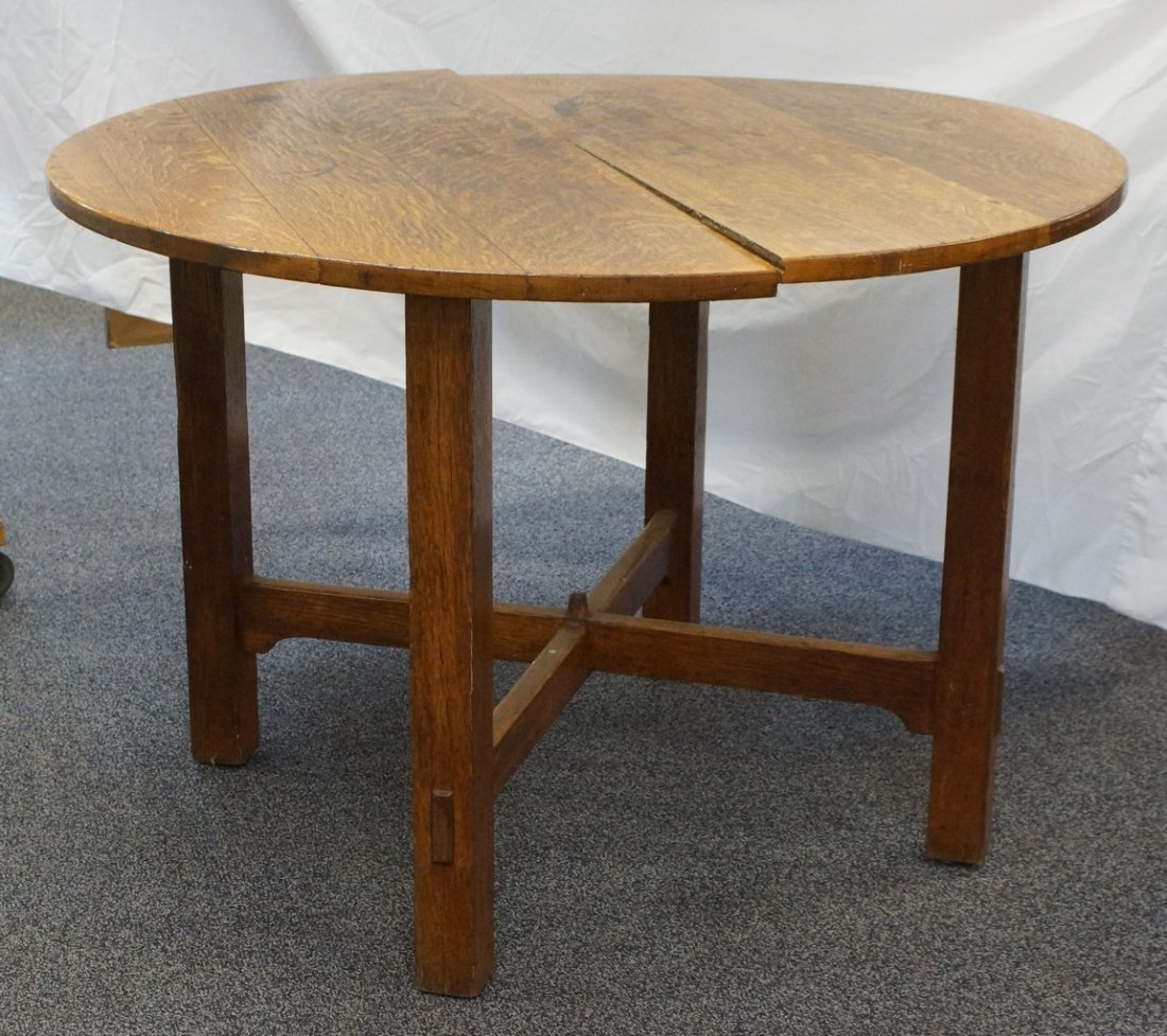 Gustav Stickley round oak center table with cross: Gustav Stickley round oak center table with cross stretcher base, top with glue line split, stains, corners of legs with nicks and bumps, imperfect finish throughout, 45" diameter