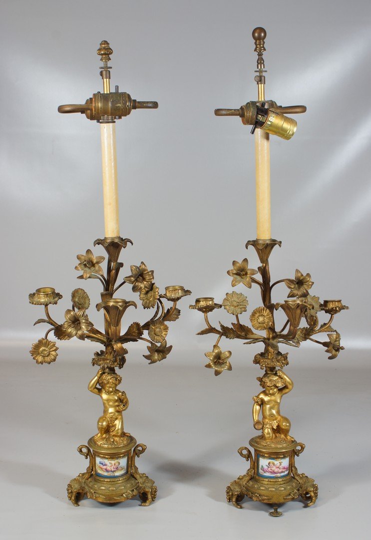 Pr French 4 arm gilt bronze cherub form candelabra with: Pr French 4 arm gilt bronze cherub form candelabra with cherub decorated porcelain panels at base (one with crack), converted to electricity, one cherub missing handheld item, 19th c, 17" tall without