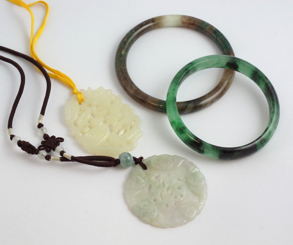 2 white jade carved pendants on rope necklaces, about: 2 white jade carved pendants on rope necklaces, about 2" in diameter, along with 2 hard stone bangle bracelets.