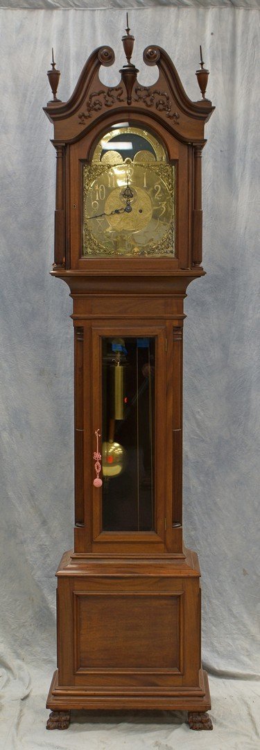 American carved mahogany hall clock, brass dial marked: American carved mahogany hall clock, brass dial marked J E Caldwell Co, with a swan's neck crest and urn shaped finials above ribbon carving, brass face with phases of the moon, free standing columns 