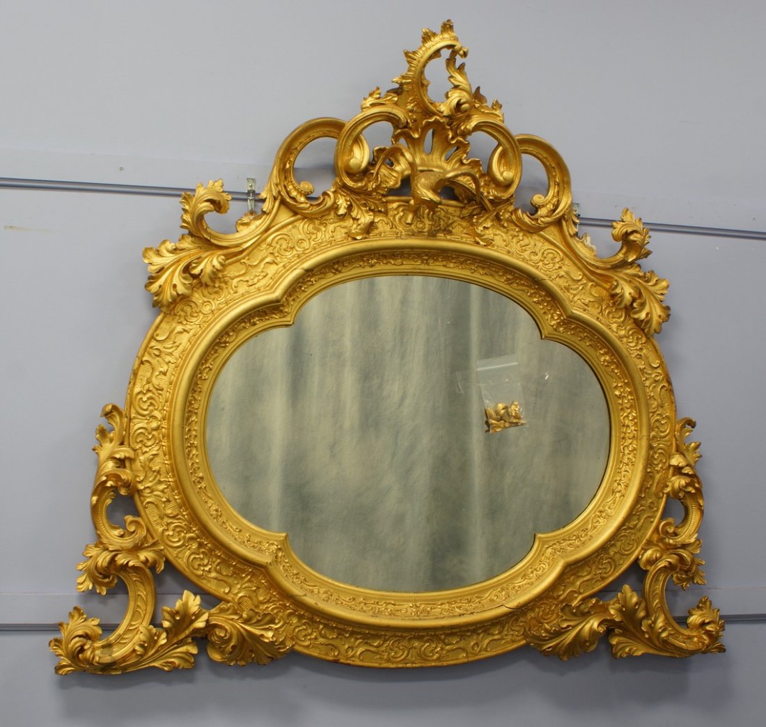Monumental size Continental shaped oval mirror with: Monumental size Continental shaped oval mirror with pierced carved crest of C-scrolls, leaves and centered by a phoenix, outset lower corners pierced carved with foliage, approximately 58" high, 66" w