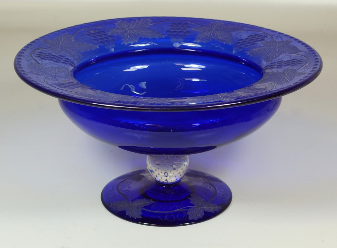 Cobalt blue Pairpoint glass centerpiece bowl, rim etche: Cobalt blue Pairpoint glass centerpiece bowl, rim etched with grapevine design, base raised on a clear glass ball with controlled bubble ball in stem, on etched base, 7-1/2" high, 14-1/2" wide