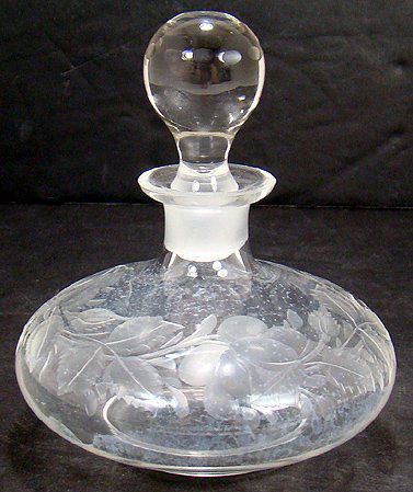 CUT GLASS COLOGNE BOTTLE: CLEAR CRYSTAL COLOGNE BOTTLE WITH ORIGINAL BALL STOPPER, 5 1/2 BY 4 1/2 INCHES. GRAVIC STYLE CUTTING AROUND THE BODY OF GARLANDS OF ROSES WITH STEMS AND LEAVES. CA. 1920. S AND I IS $15.00.