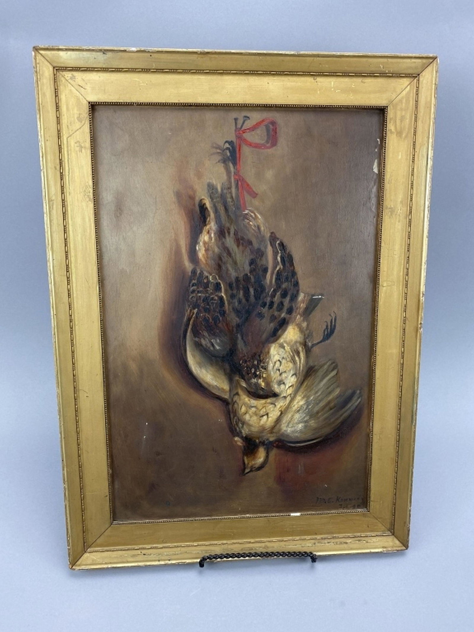 M.E. Kennedy Dead Hanging Game Painting: Oil on Board, excellent condition with a few small paint flakes, artist signature in lower right hand corner & dated, date is illegible, some crazing patina, frame is 15.5"W x 21.75"T, est. Market Det