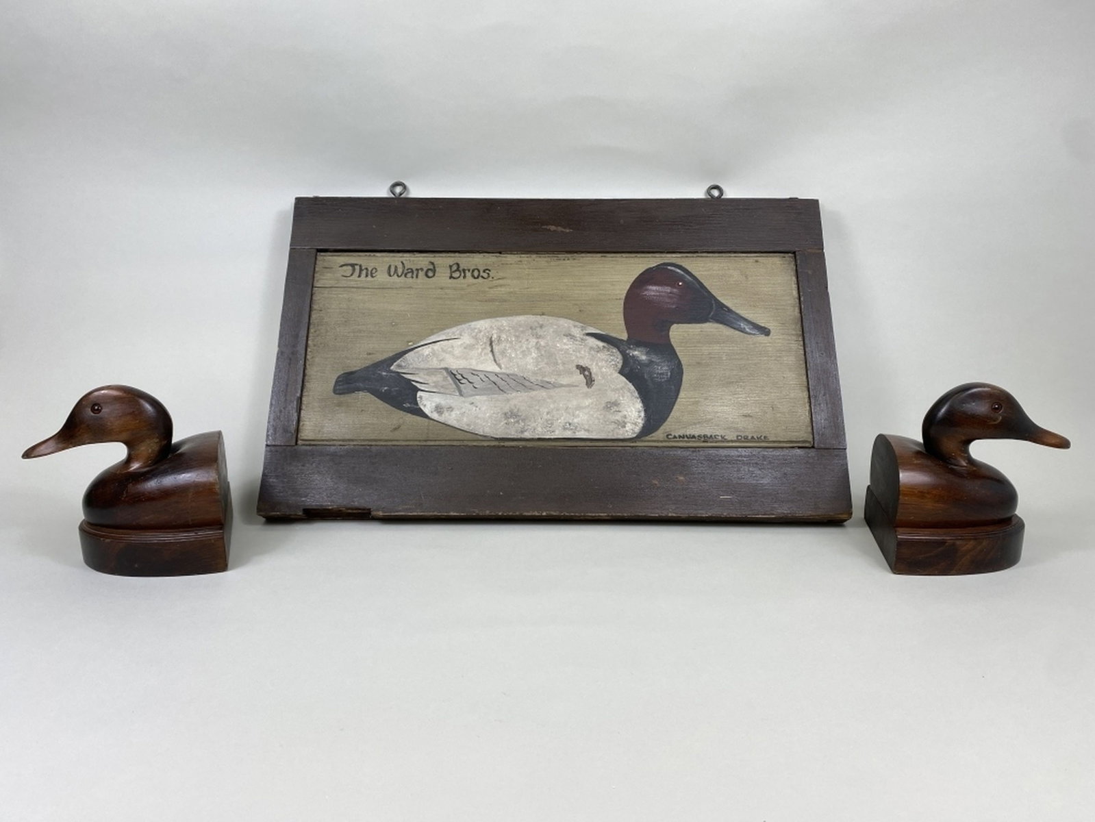 Pr of Wooden Bookends & Wall D?cor: both by unknown makers, 1 wall hanging, "The Ward Bros. Canvasback Drake" painted on what appears to be an old cupboard door, original paint, applied age, minor scuffs & dings to board, discoloration 