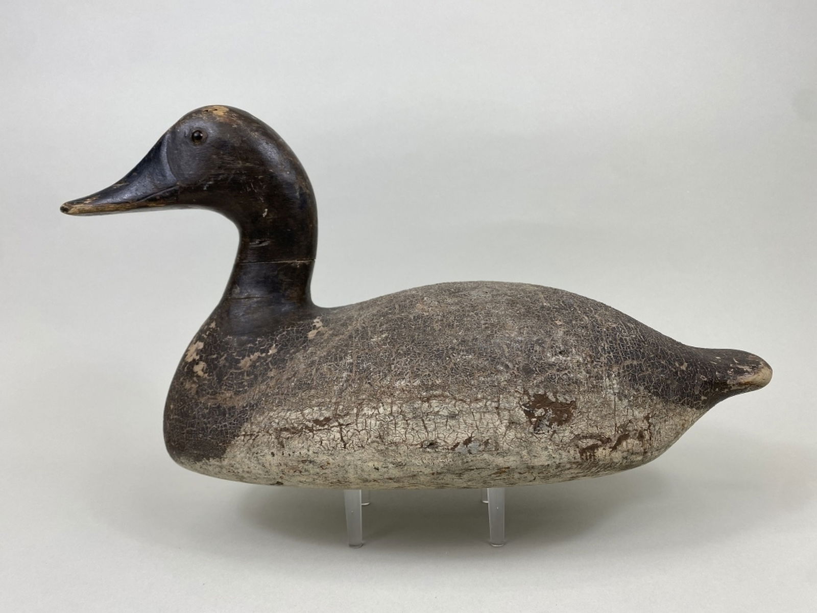 Myron Frisque Canvasback Hen Duck Decoy: Green Bay, WI, glass eyes, solid body, original paint with crazed surface, shot marks, age crack through neck, paint loss & gunning wear, inletted lead weight, 16.5"L, est. 200 - 300