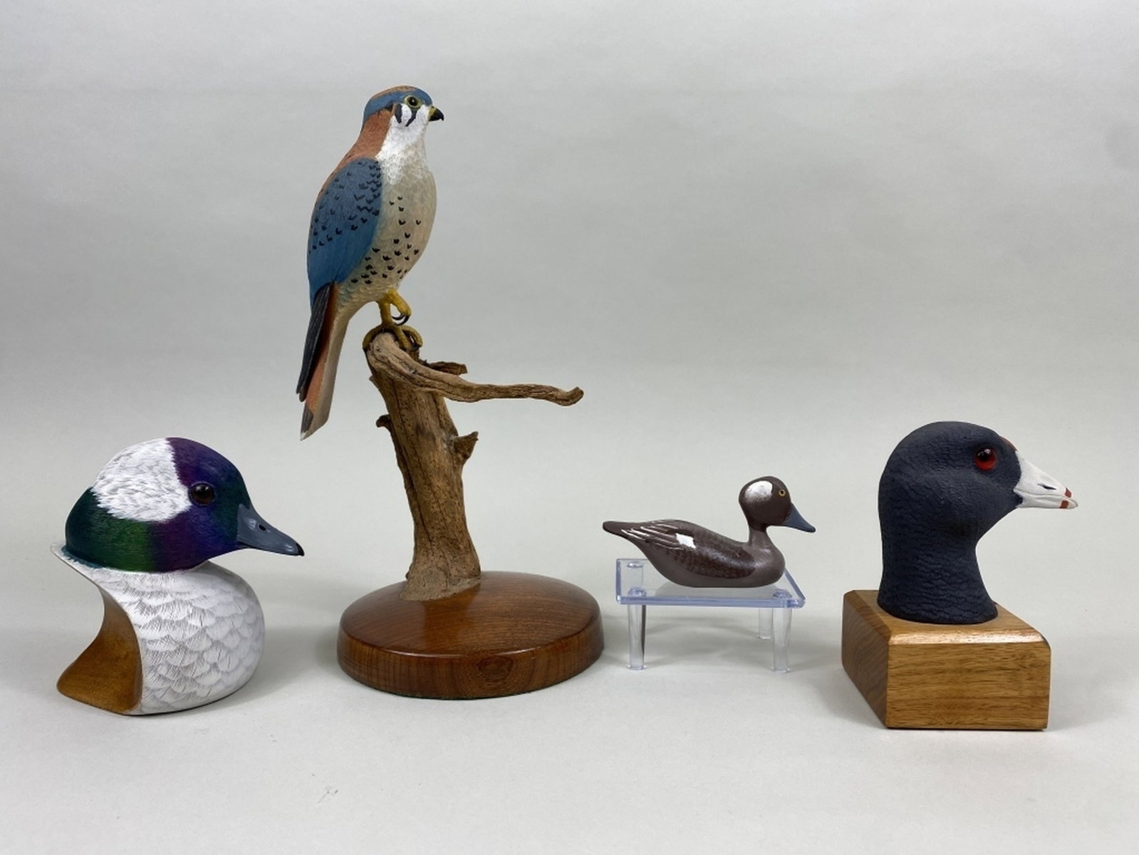 4 Miscellaneous Bird Carvings: 1 miniature bufflehead hen by Clarence "Titbird" Bauer, painted eyes, excellent original paint, name & dated 1985 on bottom, 4"L, 1 carved coot head on wooden block by unknown carver, glass eyes, exce