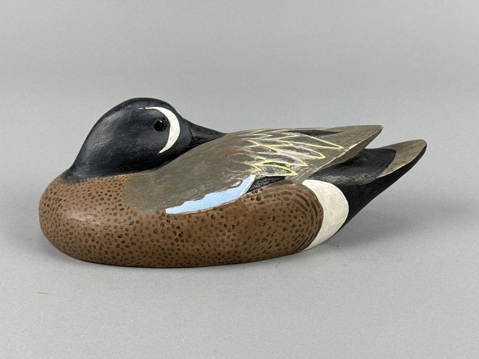 Andrew T. Beary Blue-Winged Teal: Thibodaux, LA, glass eyes, solid body, strong original paint, nice form in preening position with relief carved tail, makers brand ATB on bottom, 10"L, est. 400 - 700