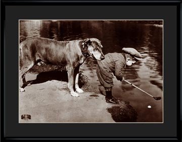 Lithograph - 11x14 Boy's Best Friend: This collectible archival photo-lithograph entitled "Boys Best Friend" taken during the 1950's captures a pet assisting his young British friend with his challenging golf shot. Comes matted and framed
