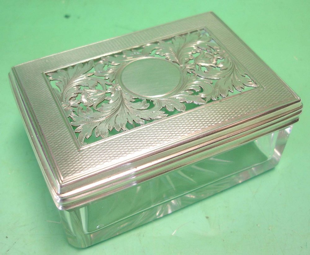 An Early Victorian Glass Trinket box.: An Early Victorian Glass Trinket box. The silver cover engine turned and finely pierced with scrolling foliage around a vacant cartouche^ the base star cut. Maker: Frances Douglas. 3 ¼” wide. Londo