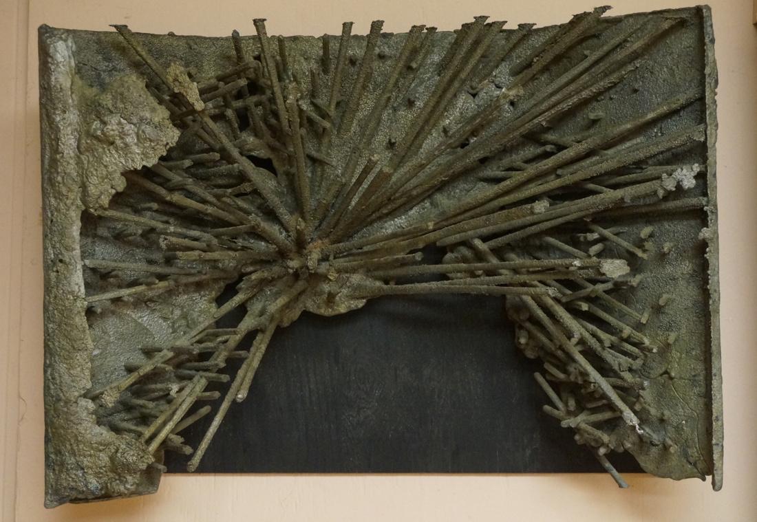 JEANNE WHORRALL Brutalist Hanging Wall Sculpture.: JEANNE WHORRALL Brutalist Hanging Wall Sculpture. Melted steel form with metal dowel details. Sculpture mounted on black plywood base. Has a metal plaque with artist name.-- Dimensions: H: 19.5 inches