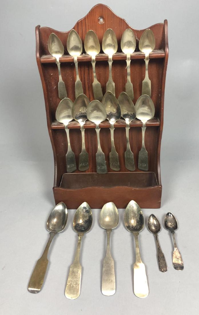 18pc Antique Fiddle back Spoons, Some Silver. Som: 18pc Antique Fiddle back Spoons, Some Silver. Some with engraved monograms. Various sizes. Comes with more recent spoon display wall shelf. -- Dimensions: H: 9 inches ---
