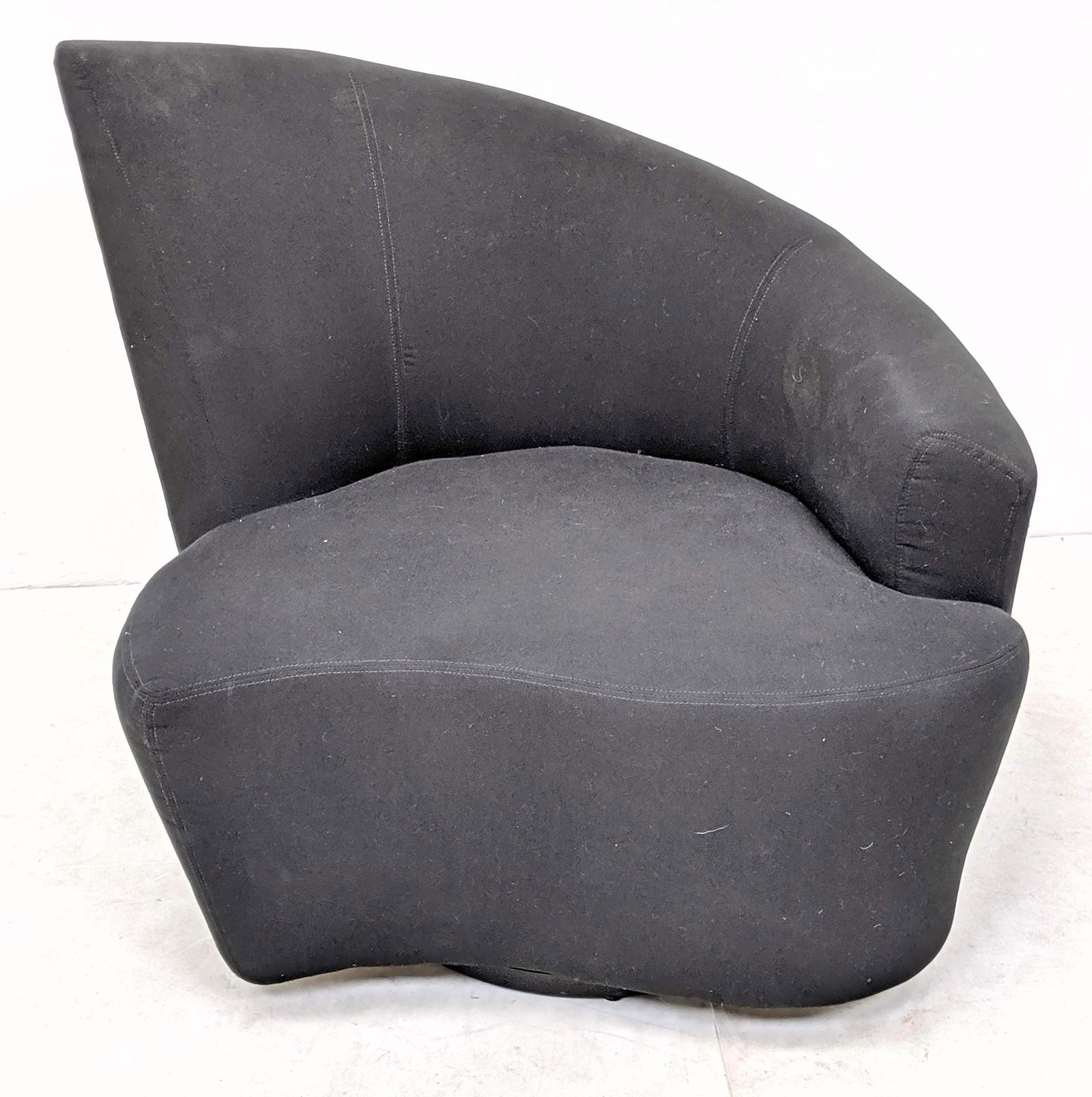 VLADIMIR KAGAN Bilbao Club Chair. Angled: VLADIMIR KAGAN Bilbao Asymmetrical Club Chair. Angled back with one arm. Cloud form seat. Black fabric upholstery. Swivels on circular base.-- Dimensions: H: 38 inches: W: 40 inches: D: 31 inches ---u