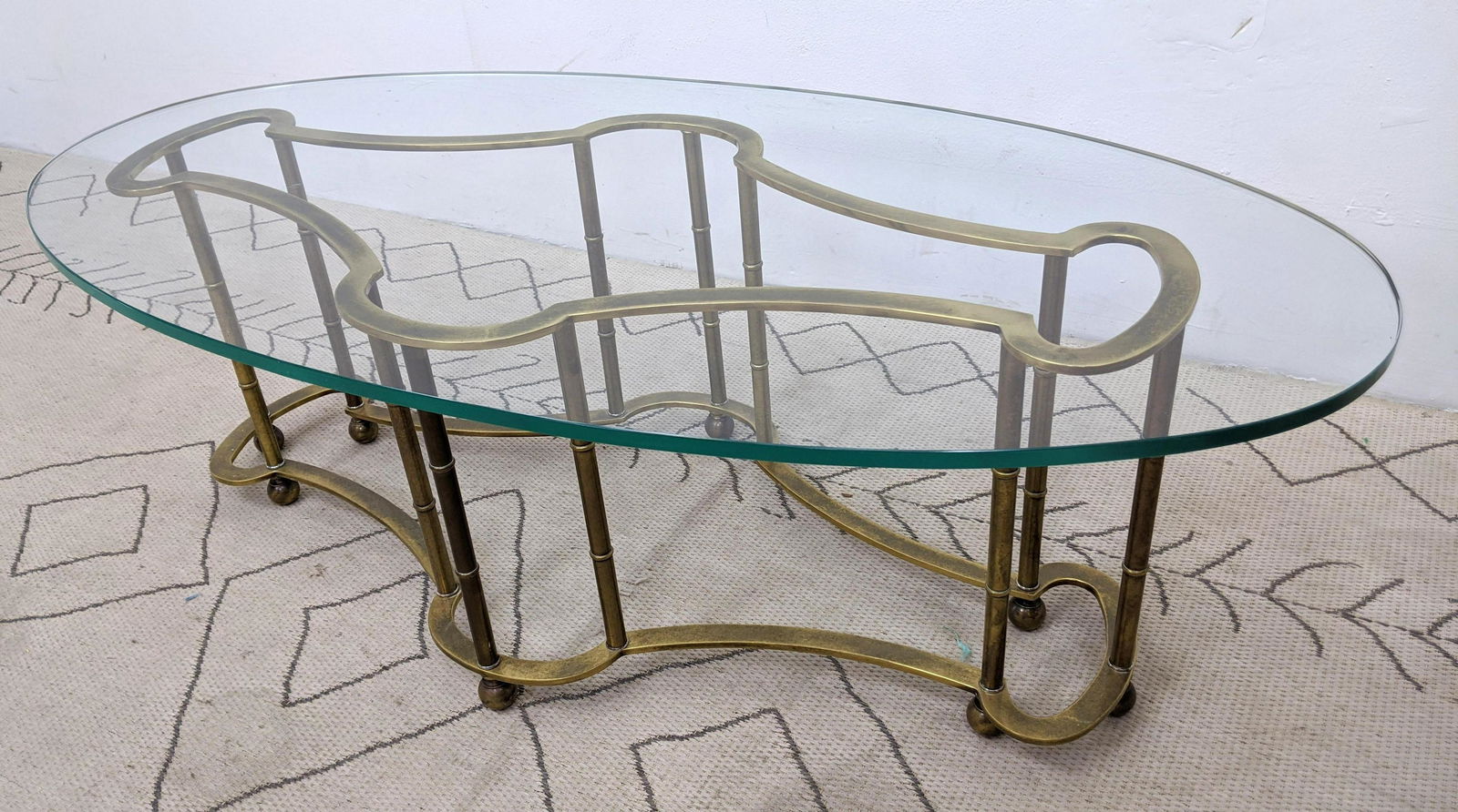 Oval MASTERCRAFT Brass & Glass Coffee Table. Shaped bra: Oval MASTERCRAFT Brass & Glass Coffee Table. Shaped brass base supports thick glass top. Antique brass finish-- Dimensions: H: 17.75 inches: W: 52 inches: D: 26.25 inches ---