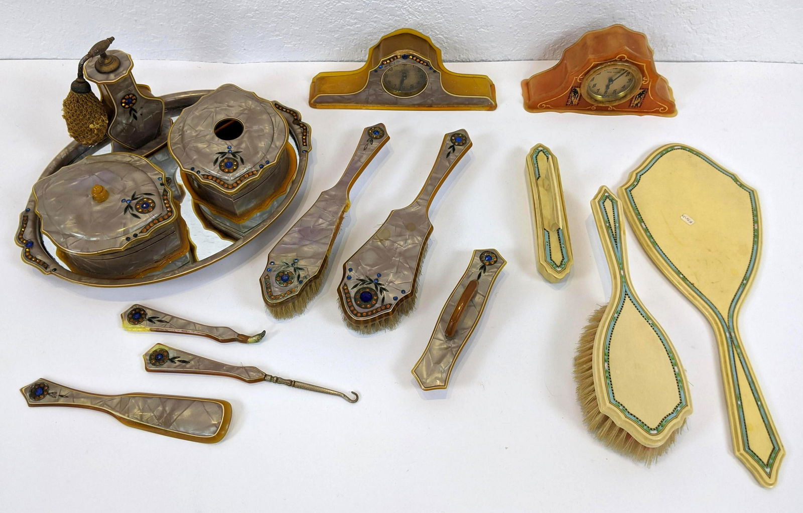 Assortment Vintage Art Deco Celluloid Dresser Accessori: Assortment Vintage Art Deco Celluloid Dresser Accessories. One set includes tray, box, hair receiver, 2 brushes, shoe horn, perfume bottle, buffer and 4 assorted tools. Celluloid clock with red crysta