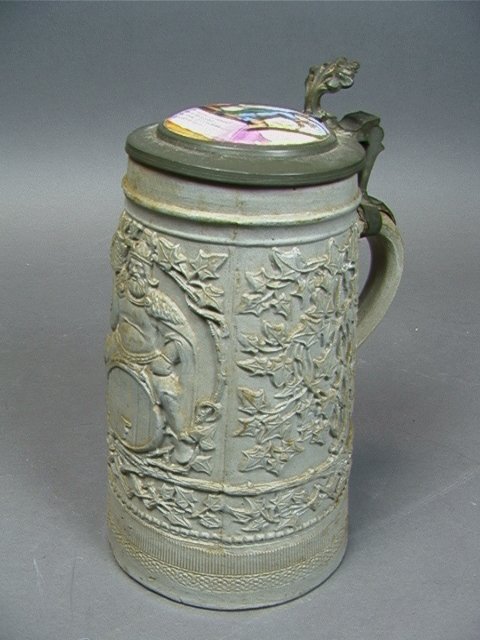 German Stein. Porcelain top. Body decorated with: German Stein. Porcelain top. Body decorated with man on a keg. Unmarked. Dimensions: H: 9.5 inches: W: 5 inches: D: 6 inches Condition (General) Please contact us with specific questions about conditi