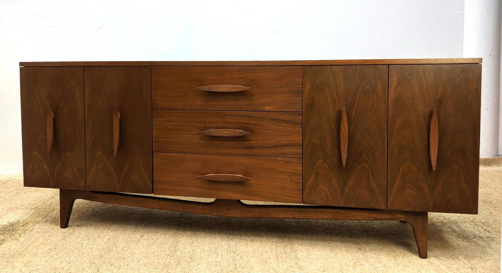 American Modern Walnut Credenza. Dresser. Chest of draw: American Modern Walnut Credenza. Dresser. Chest of drawers with sculptural wood pulls. Raised on legs. -- Dimensions: H: 32 inches: W: 78 inches: D: 20 inches ---