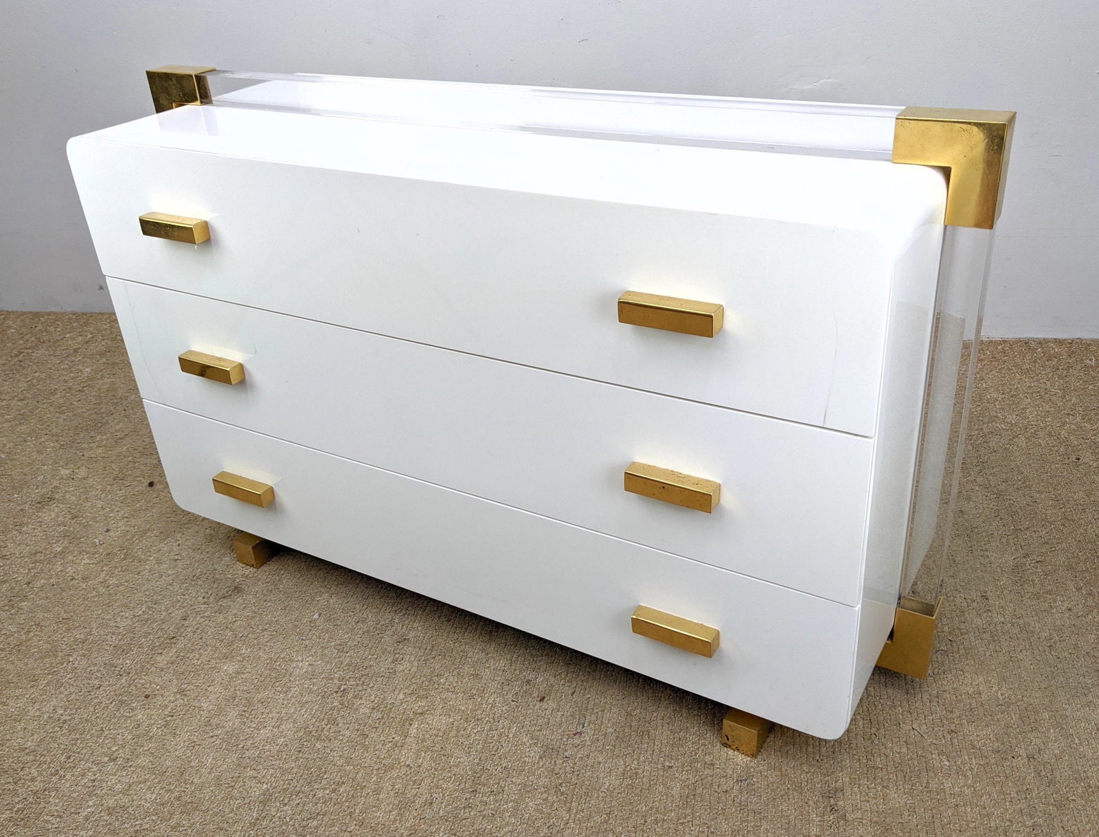 Decorator White Acrylic Bachelor's Chest Dresser: Decorator White Acrylic Bachelor's Chest Dresser Server. Lucite decorative trim with brass accents; Brass feet and pulls.-- Dimensions: H: 29 inches: W: 47 inches: D: 18 inches ---