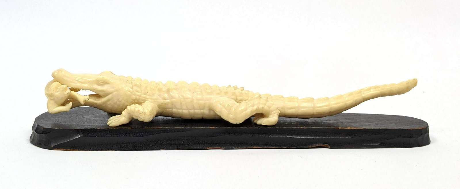 Carved Asian Figural Sculpture. Alligator has caught a: Carved Asian Figural Sculpture. Alligator has caught a little monkey. Wood Base. -- Dimensions: H: 1 inches: W: 8.5 inches: D: 1.75 inches ---